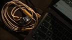 iFi Audio GO cable coiled beside a laptop with in-ear monitors