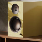 Kanto Audio TUK G2 in Gloss Butter on a wooden sideboard beside a designer lamp