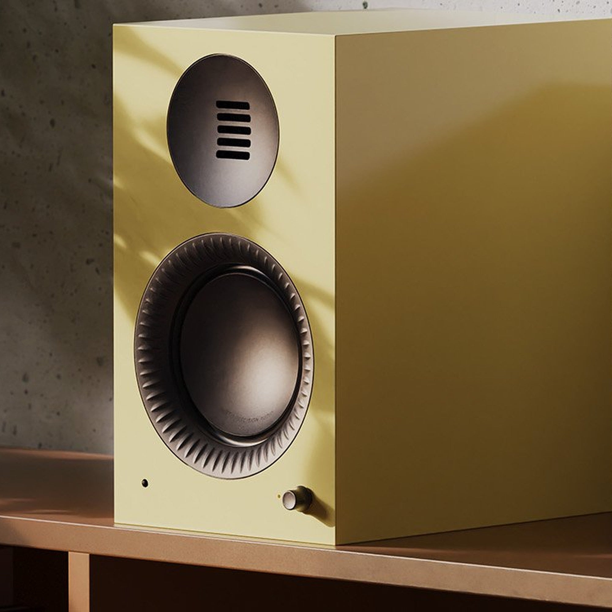 Kanto Audio TUK G2 in Gloss Butter on a wooden sideboard beside a designer lamp