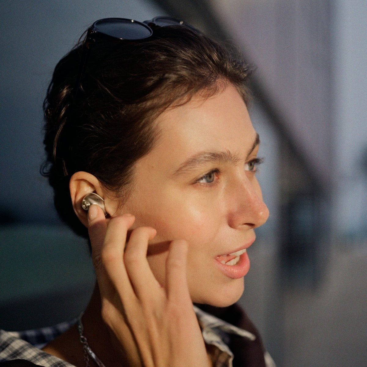 Sennheiser Momentum True Wireless 5 earbud worn in ear, evening lifestyle shot